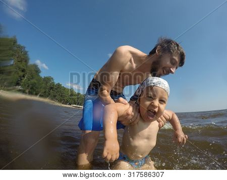 Father In Shorts Bathes His Son In Shorts In The Sea