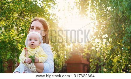 Young Loving Mother Walking With Her Little Baby On Spring Background. Cute Child And Her Mom Outdoo