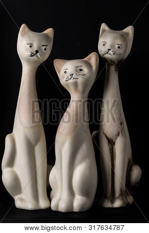 Three Different Size Porcelan Cat Figurines With Long Necks And Expressive Features Sitting Agaist A