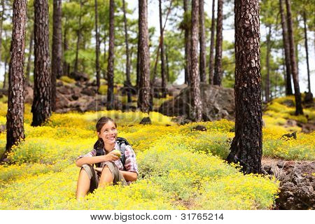 Frau Wanderer sitzen entspannen nach dem Wandern Essen Apfel im Frühlingsblumen im Waldboden. Gesamtstruktur-lan