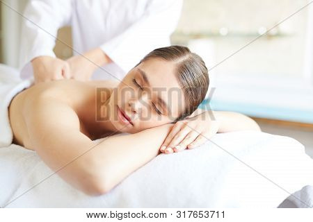 Portrait Of Beautiful Young Woman Lying On Massage Table With Eyes Closed While Enjoying Spa Treatme