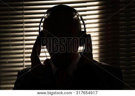Bald Man With Headphones On The Background Of Closed Blinds, Contour Lighting