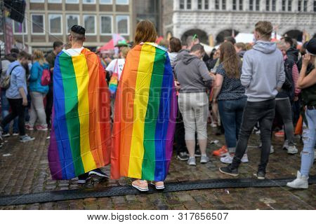 Luebeck, Germany, August 17, 2019: Two Young People From Behind Are Wearing Rainbow Flags As Capes, 