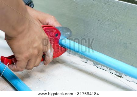 Using A Cutter For Plastic Pipes In The Repair Of Household Water Supply, Plumbing Hand Close-up.
