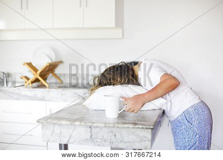 Sleppy Woman With Cup Of Coffee And Pillow On The Kitchen In Morning. Hard Morning Wake Up Concept