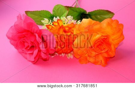 Three Beautiful Flowers On A Pink Background. Artificial Roses.
