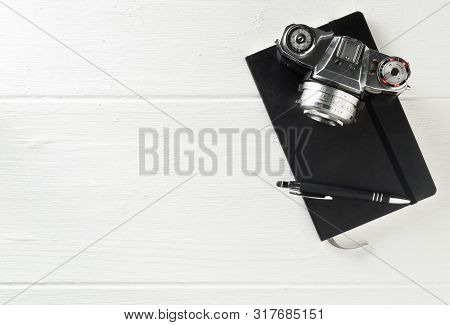 Retro Analog Film Camera With Notebook And Pen On White Wooden Table Background With Copy Space - Ph