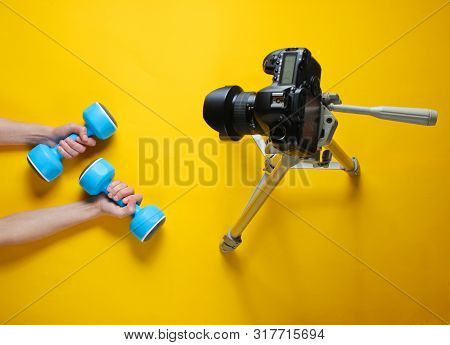 Fitness Blogger. Woman Holding Plastic Dumbbells With Her Hands And Blogging With Camera On Tripod O