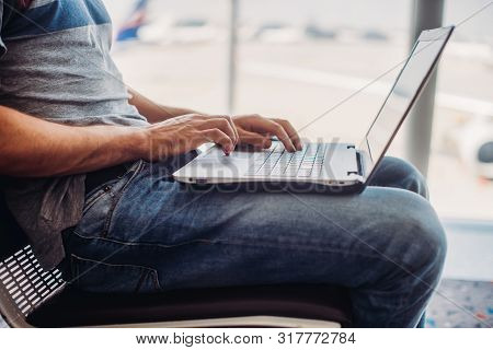 Young Man Using Laptop In Airport Terminal
