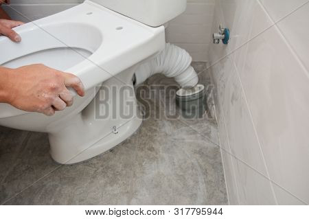 Handyman Installing Flush Toilet. Repairing, Dismantling Toilet Bowl In The Bathroom