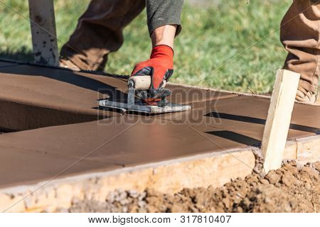 Construction Worker Using Hand Groover On Wet Cement Forming Coping Around New Pool.