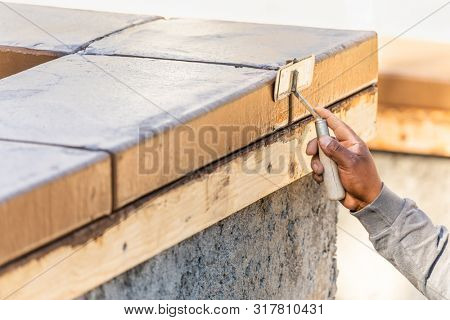 Construction Worker Using Hand Groover On Wet Cement Forming Coping Around New Pool.