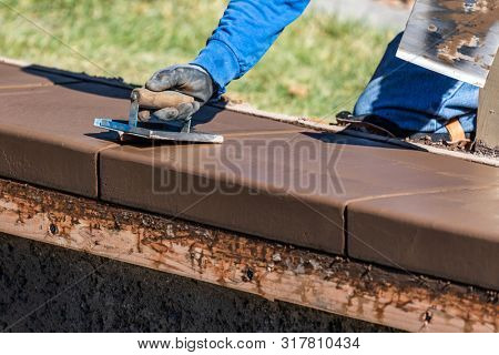 Construction Worker Using Hand Groover On Wet Cement Forming Coping Around New Pool.