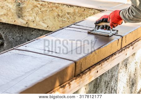 Construction Worker Using Hand Groover On Wet Cement Forming Coping Around New Pool.