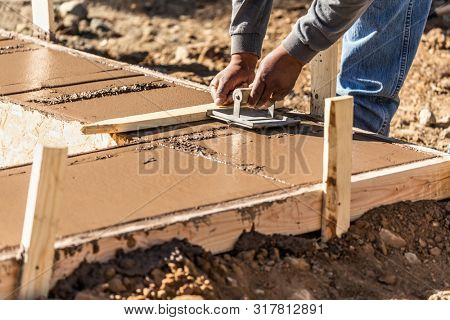 Construction Worker Using Hand Groover On Wet Cement Forming Coping Around New Pool.