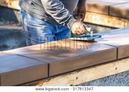 Construction Worker Using Hand Groover On Wet Cement Forming Coping Around New Pool.