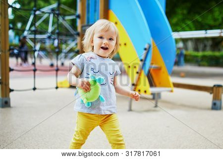 Adorable Toddler Girl Having Fun On Playground. Outdoor Activities For Kids