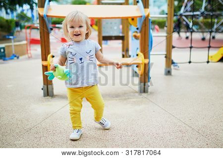 Adorable Toddler Girl Having Fun On Playground. Outdoor Activities For Kids