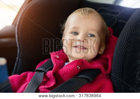 Cute Caucasian Toodler Boy Sitting In Child Safety Seat In Car During Road Trip. Adorable Baby Smili