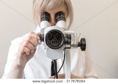 Young Female Professional Gynecologist In The Working Process, Looks Into The Colposcope.