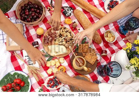 Top View People Take Food From Checkered Picnic Blanket. Outdoor Summer Family Picnic.