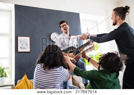 A Group Of Young Friends With Guitar Indoors At Home, House Sharing Concept.