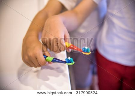 Child's Hands Holding Toothbrush On Pink Backgroubd. Healty Care Teeth Concept. Copy Space For Your 