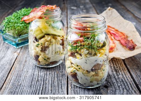 Brotzeit im Glas â traditional Bavarian snack with ham, eggs and black bread in a glass as closeup on a wooden board 