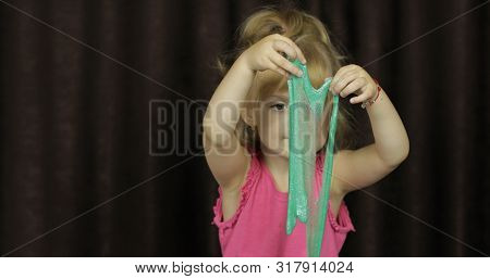 Child Having Fun Making Green Slime. Kid Playing With Hand Made Toy Slime. Funny Kid Girl. Blowing B