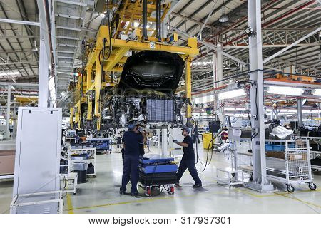 Workers Assembles Cars At Automobile Assembly Line Production Plant