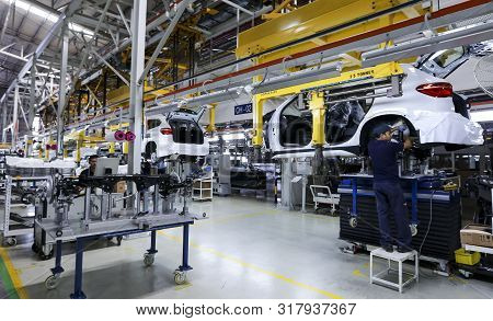 Workers Assembles Cars At Automobile Assembly Line Production Plant