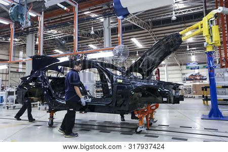 Workers Assembles Cars At Automobile Assembly Line Production Plant