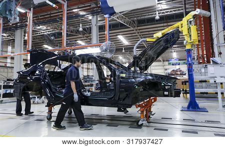 Workers Assembles Cars At Automobile Assembly Line Production Plant