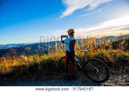 Mountain biking woman riding on bike in autumn mountains forest landscape. Woman cycling MTB flow trail track. Outdoor sport activity.
