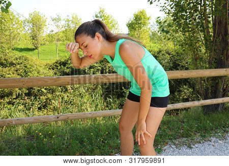 Woman Bent Over In Exhaustion And Catching Her Breath After A Running Session.