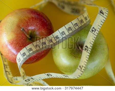 Bodegon Mounted On A Yellow Background And Composed Of Two Apples And A Tape To Measure The Waist