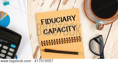 Notebook With Text Fiduciary Capacity On The Office Table, Documents, Calculator, Glasses And Pen