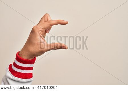 Hand of caucasian young man showing fingers over isolated white background picking and taking invisible thing, holding object with fingers showing space