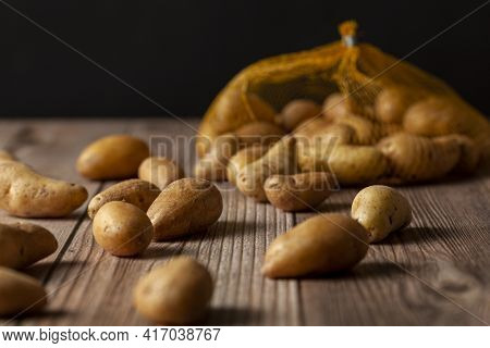 Shallow Depth Of Field Dark Image Of Small Irregular Shaped Ratte Potatoes Scattered On The Surface 