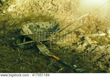 Dirty Wheelbarrow And Shovel On Bare Ground.high Quality Photo.