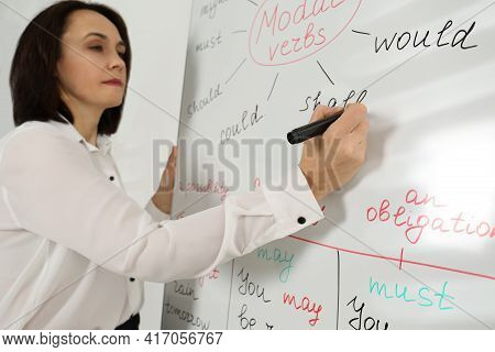 English Teacher Giving Lesson On Modal Verbs Near Whiteboard In Classroom