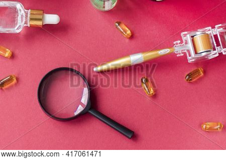 Magnifying Glass Against The Background Of Face Serums And Dermoroller