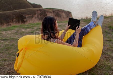 Asian Woman Lying On Inflatable Sofa Lamzac While Resting With Laptop At Sunset On The Mountain