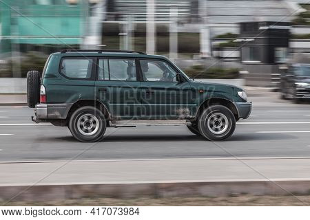 Car Moving At High Speed On The City Street. Old Green Suv Car Drives Fast Through The City With Mot