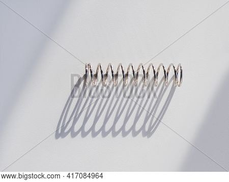 Metal Mainspring On White Background. Flexible Chrome Tube. Corrugated Object On Geometrical Banner 