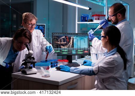Team Of Scientist Working On Dna, Analyzing Blood Sample And Using Micropipette