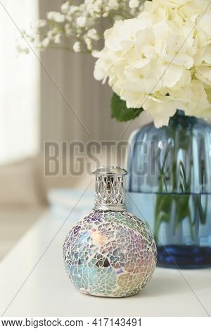Stylish Catalytic Lamp With Beautiful Bouquet On White Table In Living Room. Cozy Interior
