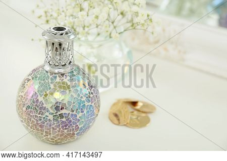 Closeup View Of Stylish Catalytic Lamp With Beautiful Gypsophila And Earrings On White Table, Space 