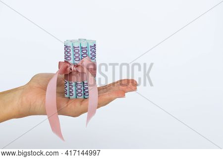 Ukrainian Banknotes With A Gift Ribbon In A Hand.