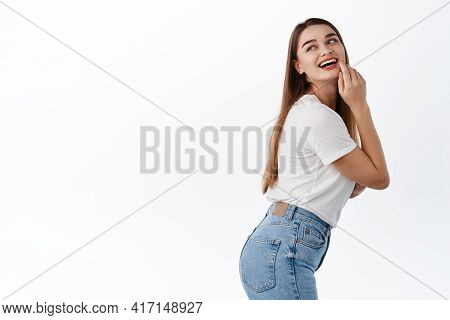 Beautiful Fit And Healthy Girl In T-shrit And Jeans, Smiling, Touching Clean Hydrated Facial Skin An